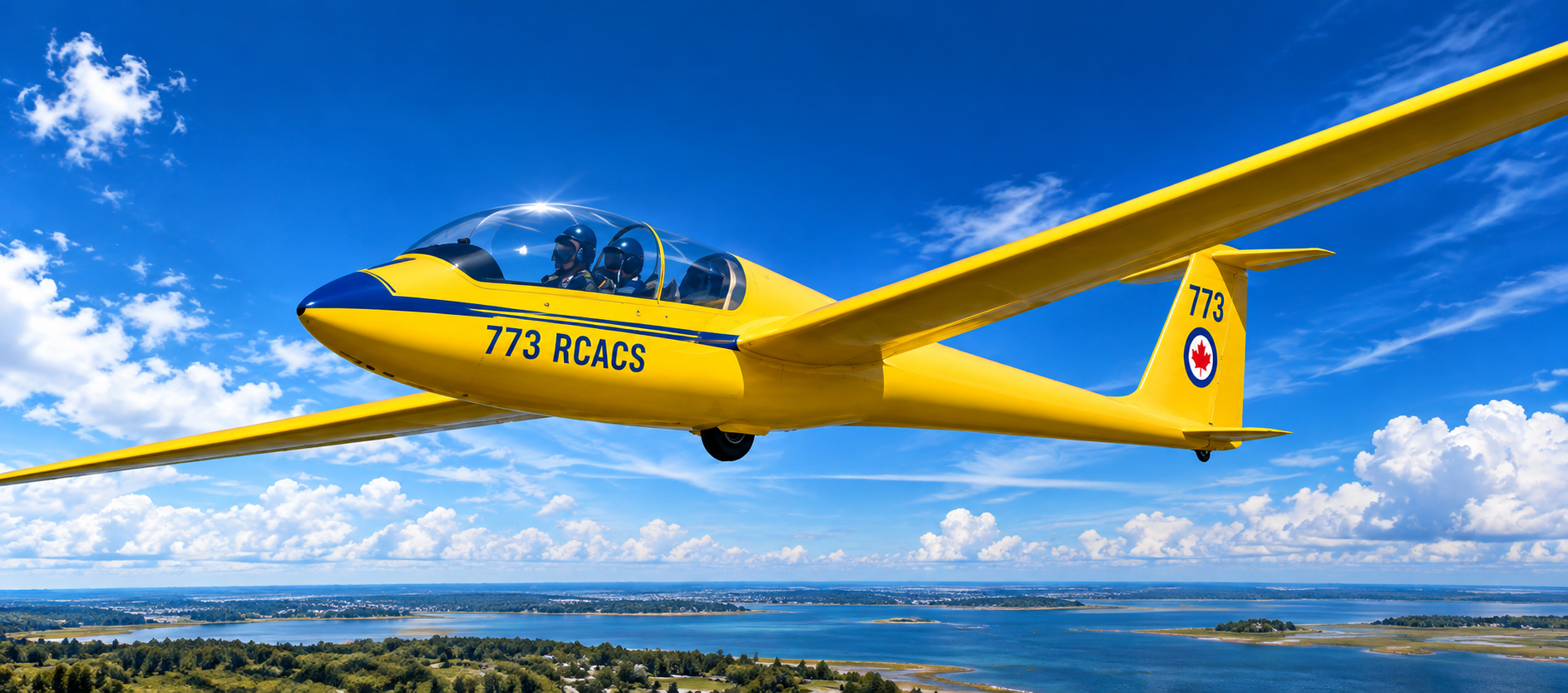 Yellow 773 RCACS glider flying over a coastal landscape